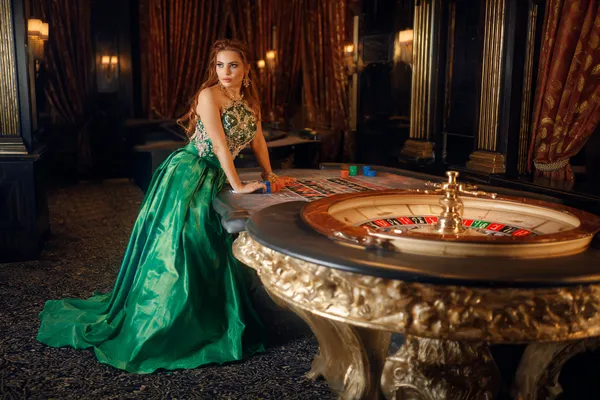 A woman in a luxurious green gown next to an ornate roulette wheel, capturing the upscale casino mood of 83JLPH.