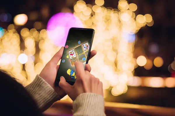 A player using their smartphone during a festive local event, representing 83JLPH’s fully mobile-friendly casino.